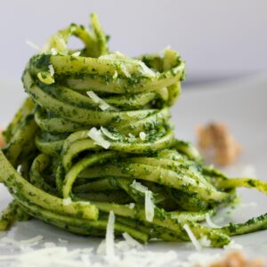 Close-up of delicious pesto pasta, beautifully plated with parmesan shavings.