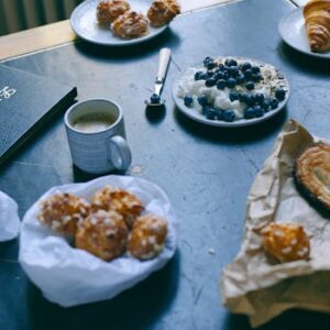 A charming breakfast scene featuring pastries, coffee, and a blueberry yogurt parfait on a table.