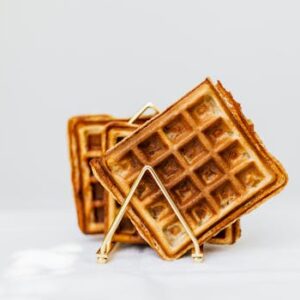 Close-up of delicious golden brown waffles stacked on a white surface with copy space.